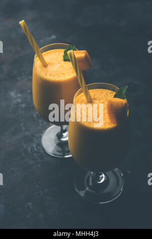 Mango Lassi oder Smoothie in grosses Glas mit mint Blatt. Flankendehnung über bunten Hintergrund isoliert. Selektiver Fokus Stockfoto