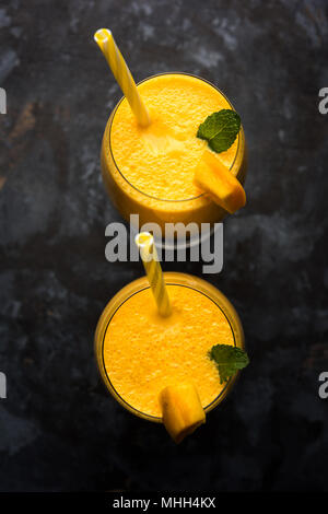 Mango Lassi oder Smoothie in grosses Glas mit mint Blatt. Flankendehnung über bunten Hintergrund isoliert. Selektiver Fokus Stockfoto