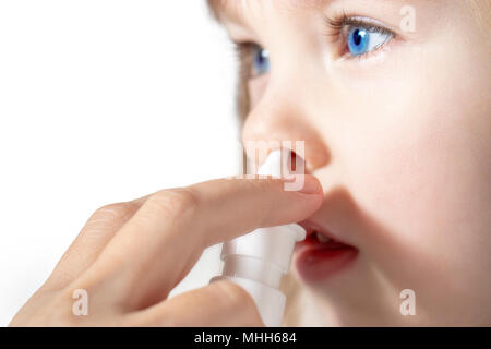 Mutter mit nasenspray Ihr kleines Mädchen in der Nähe bis zu kurieren. Stockfoto