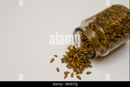 Vintage Glas Glas gefüllt mit geschälte Sonnenblumenkerne und verschüttet. Essen isoliert auf weißem Hintergrund mit Text oder Elemente hinzuzufügen. Stockfoto