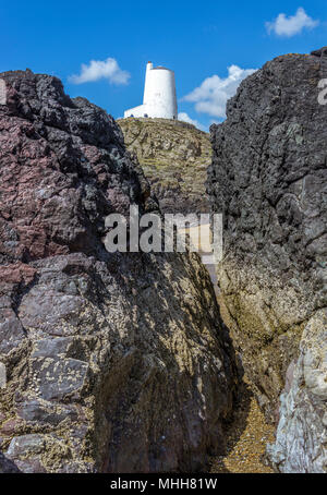 Eine Ansicht von Twr Mawr Leuchtturm auf llanddwyn Island, Anglesey, Nordwales durch eine Lücke in der Lava Säulen. Stockfoto