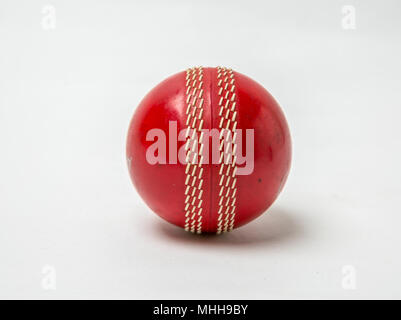 Nahaufnahme eines roten Cricket Ball auf weißem Hintergrund. Stockfoto