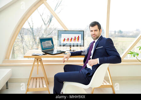Portrait von zuversichtlich finanzielle Investitionen Geschäftsmann sitzen vor dem Laptop während der Arbeit auf die finanzielle Berichterstattung. Stockfoto