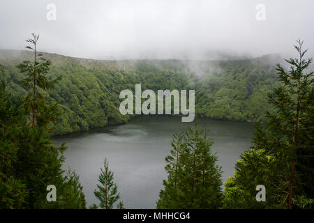 Atemberaubende vulkanische See umgeben von Wald und Nebel Stockfoto