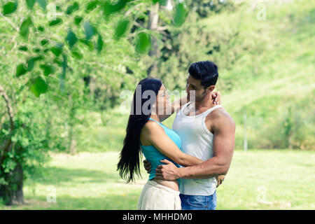 Glücklich lächelnde Paar Festlegung auf grünem Gras in einem schönen Park Stockfoto