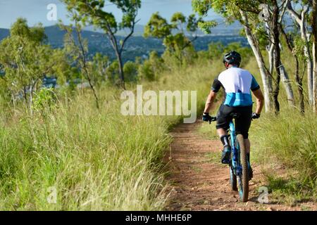 Männliche Fahrrad Reiter auf einem Mountainbike Bergabfahren auf einer Schotterpiste, Mount Stuart Wanderwege, Townsville, Queensland, Australien Stockfoto