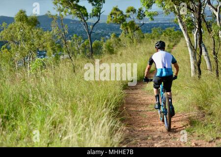 Männliche Fahrrad Reiter auf einem Mountainbike Bergabfahren auf einer Schotterpiste, Mount Stuart Wanderwege, Townsville, Queensland, Australien Stockfoto