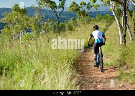 Männliche Fahrrad Reiter auf einem Mountainbike Bergabfahren auf einer Schotterpiste, Mount Stuart Wanderwege, Townsville, Queensland, Australien Stockfoto