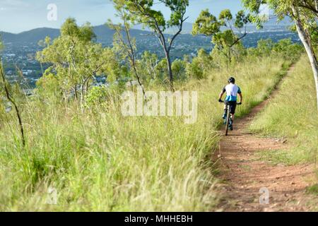 Männliche Fahrrad Reiter auf einem Mountainbike Bergabfahren auf einer Schotterpiste, Mount Stuart Wanderwege, Townsville, Queensland, Australien Stockfoto