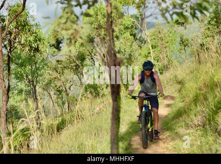 Männliche Fahrrad Reiter auf einem Mountainbike Bergabfahren auf einer Schotterpiste, Mount Stuart Wanderwege, Townsville, Queensland, Australien Stockfoto