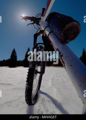 Mountainbike im Schnee, Sonne, blauen Himmel. Winter Fahrrad Ausbeutung in den Bergen Stockfoto