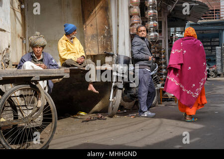 Männer ahnging herum auf Straße Ecke als Frau geht vorbei. Udaipur, auch bekannt als die Stadt der Seen, das Venedig des Ostens, ist die historische Hauptstadt des Königreichs menof Mewar, Rajasthan. Stockfoto