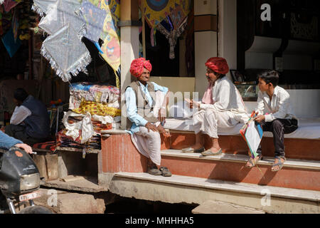 Zwei Männer in traditionellen roten Turbane und ein Junge außerhalb ihrer Shop sitzen. Bundi, Rajasthan. Indien Stockfoto