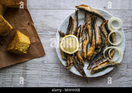 Türkische Hamsi Tava mit Cornbread/Frittierte Sardellen auf weißem Holz- Oberfläche. Stockfoto