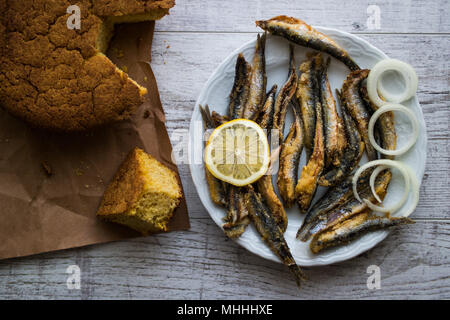 Türkische Hamsi Tava mit Cornbread/Frittierte Sardellen auf weißem Holz- Oberfläche. Stockfoto