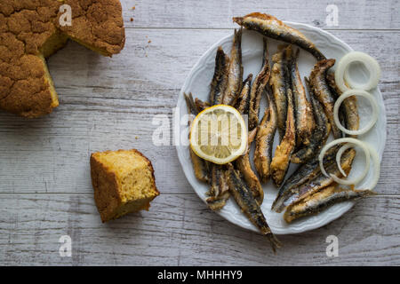 Türkische Hamsi Tava mit Cornbread/Frittierte Sardellen auf weißem Holz- Oberfläche. Stockfoto