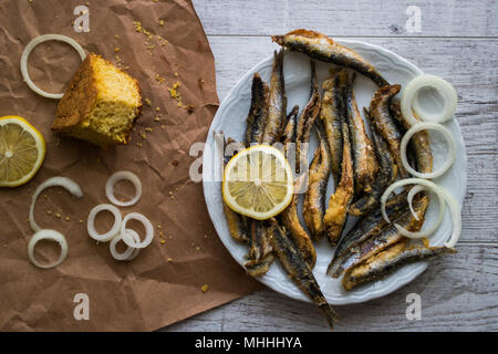 Türkische Hamsi Tava mit Cornbread/Frittierte Sardellen auf weißem Holz- Oberfläche. Stockfoto