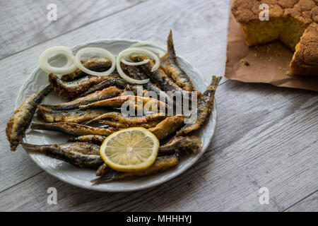 Türkische Hamsi Tava mit Cornbread/Frittierte Sardellen auf weißem Holz- Oberfläche. Stockfoto