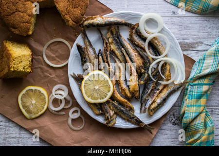 Türkische Hamsi Tava mit Cornbread/Frittierte Sardellen auf weißem Holz- Oberfläche. Stockfoto