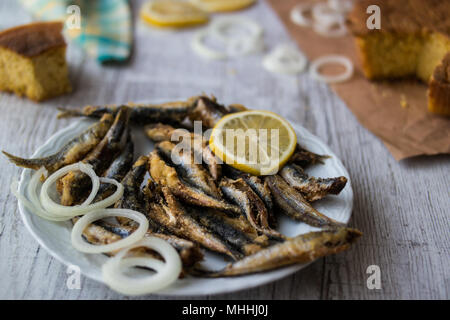 Türkische Hamsi Tava mit Cornbread/Frittierte Sardellen auf weißem Holz- Oberfläche. Stockfoto