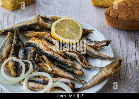 Türkische Hamsi Tava mit Cornbread/Frittierte Sardellen auf weißem Holz- Oberfläche. Stockfoto