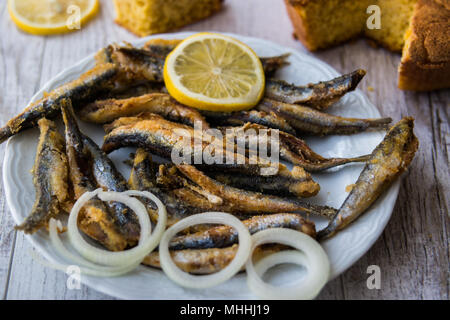 Türkische Hamsi Tava mit Cornbread/Frittierte Sardellen auf weißem Holz- Oberfläche. Stockfoto