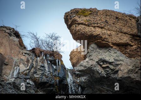 Gefrorenen Wasserfall, in der Nähe von Svinafellsjokull glazialen Zunge, Skaftafell National Park. Eiszapfen hängen aus Felswand mit blauer Himmel Stockfoto