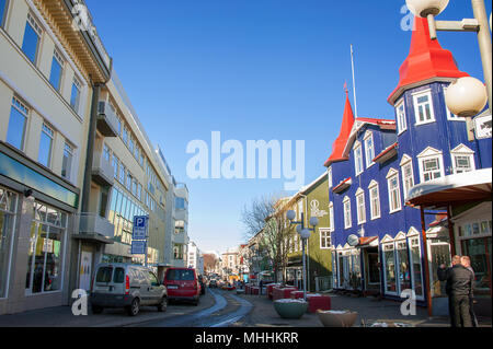 Farbenfrohe Gebäude in der Main Street, im Stadtzentrum von Akureyri, Island. Menschen und geparkte Fahrzeuge in der Fußgängerzone Hafnarstraeti Stockfoto