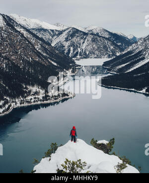 Malerischer Blick auf Mann stand am Rand und auf der Suche nach Winter Berge und See, Tirol, Österreich Stockfoto