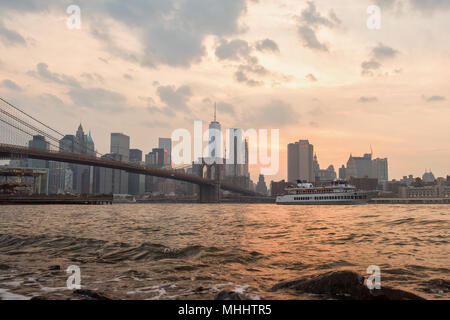 NEW YORK - USA - Juni, 12 2015 Fähre vorbei unter Manhattan Bridge bei Sonnenuntergang Stockfoto