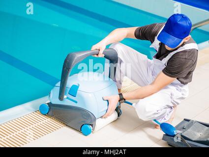 Pool Staubsauger. Kaukasische Schwimmbäder Techniker mit der Reinigung der Maschine. Stockfoto