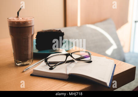 Still life: Notebook mit Gläsern, Kuchen und Kaffee. Arbeiten oder Planung Konzept Stockfoto