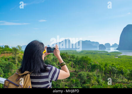 Junge Reisende Frau Backpacker Nutzung Handy nehmen Sie ein Foto der schönen Sonnenaufgang Natur an Spitze von Mountain View, Freiheit Fernweh Konzept, Khao S Stockfoto