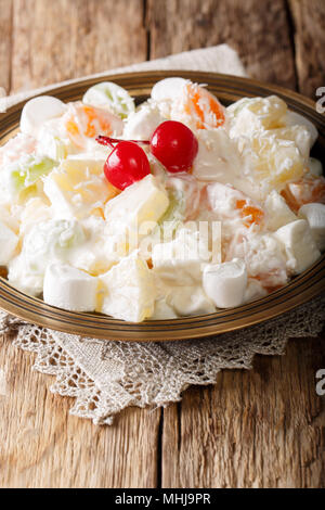 Leckere süße Frucht Salat Ambrosia aus Ananas, Mandarinen, Weintrauben und marshmelow mit Vanille Joghurt close-up auf einem Teller. Vertikale Stockfoto