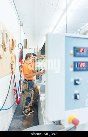 Zwei Tischler Reinigung Furnier Maschine in der Werkstatt Stockfoto