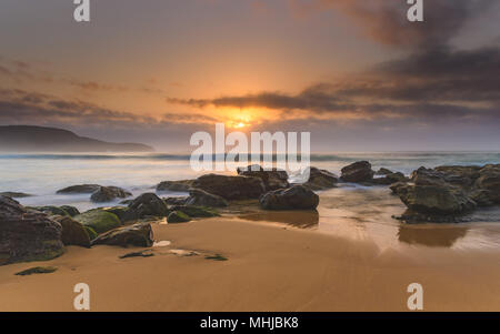 Hazy Rocky Seascape - Erfassung der Sonnenaufgang von Ettalong Beach an der Central Coast, NSW, Australien. Stockfoto