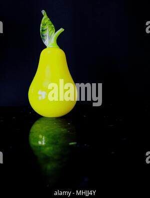 Gelbe Zierbirne aus Glas auf glänzender Oberfläche. Stockfoto