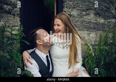 Junge stilvolle Mode Paar in Liebe in Island. Frau und Mann umarmen und möchten einander zu küssen. Stein Berge und isländischer Haus im Hintergrund. Stockfoto