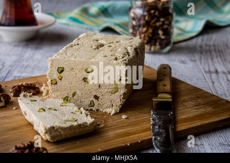 Scheiben von Halva/Helva mit Erdnuss, Walnuss und Tee auf einem Holz- Oberfläche. Stockfoto