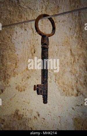 Rostiges Metall Schlüssel mit einem verputzten Wand im Hintergrund. Hochformat. Stockfoto