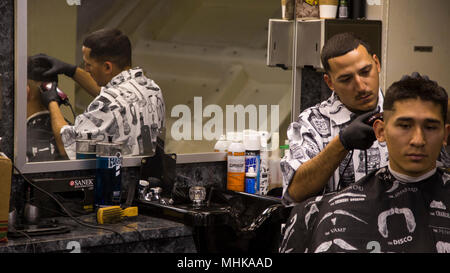 Sgt. Richard "der Friseur" Bonand, ein Marine mit Marine Fighter Attack Squadron 211, 13 Marine Expeditionary Unit, die derzeit die Aufgabe als die ausgehuniform Friseur an Bord der Wasp-Klasse schwimmfähige Schiff USS Essex (LL 2), Cpl. Ernesto Barba Lopez, crash-Feuerwehr, Marine Medium Tiltrotor Squadron 166, einen Haarschnitt, März 27,2018. Das Essex Amphibious Ready Gruppe und 13 MEU erstmals voll integrierte vor ihrer Bereitstellung. Amphibische Squadron, MEU integration Training eine entscheidende Einsatz übung, die Navy-Marine Corps Team schnell zu planen und komplexe ausführen Stockfoto