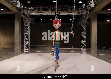 London, Großbritannien. 2. Mai 2018. Jordan Wolfson farbigen Skulptur, eine groß angelegte animatronic Installation in den Tanks in der Tate Modern. Es verfügt über eine bedrohliche Marionette über 7 Meter hoch, die angehoben wird, gezogen, gezerrt und auf den Boden fiel durch mechanisierte Ketten an beiden Extremitäten angebracht. Die Abbildung bezieht sich auf verschiedene Darstellungen von Kindheit aus der amerikanischen Popkultur. Mit digitalen Bildern für Augen ausgestattet, Sensoren ermöglichen die Marionette den Betrachter mit ihren starren zu beheben, da es Mund eine kryptische Liste der bedrohlichen Aussagen. Credit: Guy Bell/Alamy leben Nachrichten Stockfoto