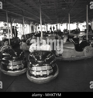 1960, historische, zwei attraktive junge Frauen zusammen reiten in einer offenen dodgem oder Stoßfänger Auto an der Battersea Kirmes, Battersea Park, London, England, UK. Die Kirmes war im Park als Teil des Festivals 1951 von Großbritannien feiern erbaut und war eine große Attraktion für junge Leute und Familien, die in diesem Zeitalter. Die dodgem Fahrt war im Besitz der Botton Bros betrieben - ihr Name ist auf den Autos - Albert und Jim Knopf, der in einem fairen Reisen um London und Südengland wuchs. Stockfoto