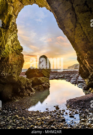 Blick auf Felsen durch eine Höhle und felsenpools bei Sonnenuntergang an der Küste, Freshwater Bay Stockfoto