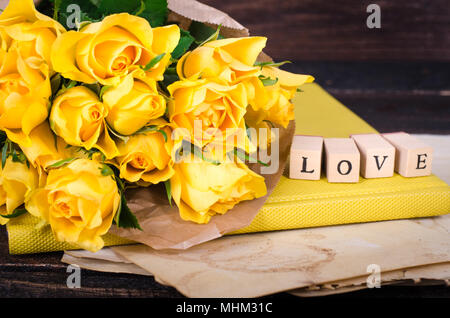Holzwürfel mit Aufschrift LIEBE DICH und Bukett von gelben Blumen auf vintage Papier, Holz- Hintergrund. Selektive konzentrieren. Stockfoto
