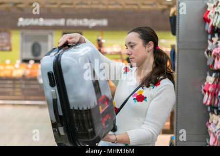 Eine junge Frau wählt einen Koffer für Reisen in die Mall. Stockfoto