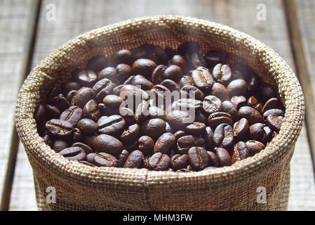 Nahaufnahme Kaffee aus frisch gemahlenen Bohnen halten Sie im Beutel nach Vermischung auf Holz Tisch. Stockfoto