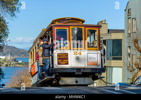 Street Cable Car - eine Seilbahn hinauf auf den Gipfel des steilen Russian Hill am Hyde St, mit Alcatraz im Hintergrund. San Francisco, CA, USA.