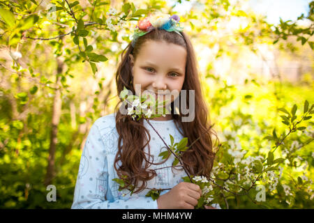 Kleines Mädchen mit einem Kranz auf dem Kopf und einem Blumenstrauß in der Hand auf einer Lichtung von Löwenzahn. Sonnigen Tag Stockfoto