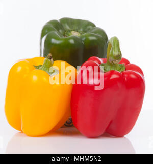 Drei farbenfrohe Paprika in Grün, Gelb und Rot auf weißem Hintergrund Stockfoto